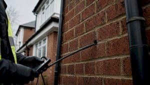 Surveyor inspecting UK home's cavity wall with borescope