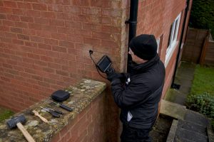 Surveyor inspecting cavity wall with borescope