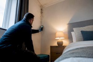 Surveyor investigating recurring mould in UK rental bedroom